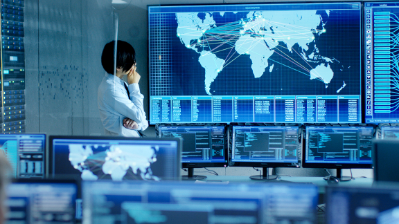 An employee is analyzing the feed from the computers on a big screen