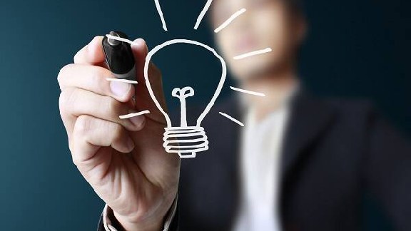 A person in suit in background is writing a bulb on the screen interface