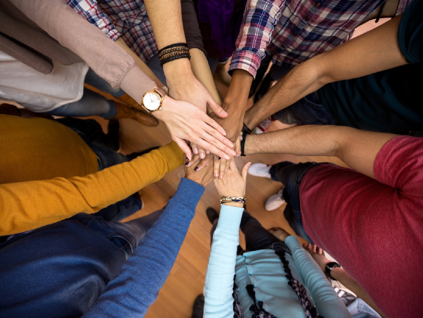 Close-up of hands of people placed on one another as in a huddle
