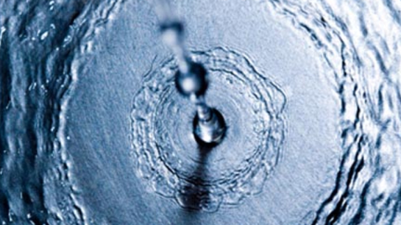 Close up drops of water falling on the ground and creating ripples