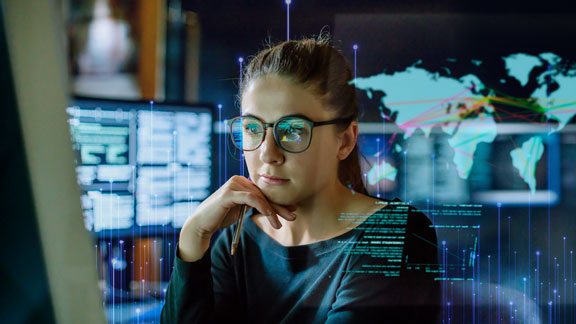 Woman using a desktop in a control room, overlaid with a graphic of transmission nodes
